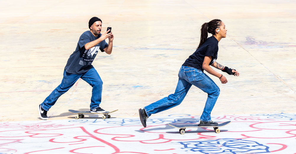 Mann folgt mit Smartphone filmend einer Rollerskaterin